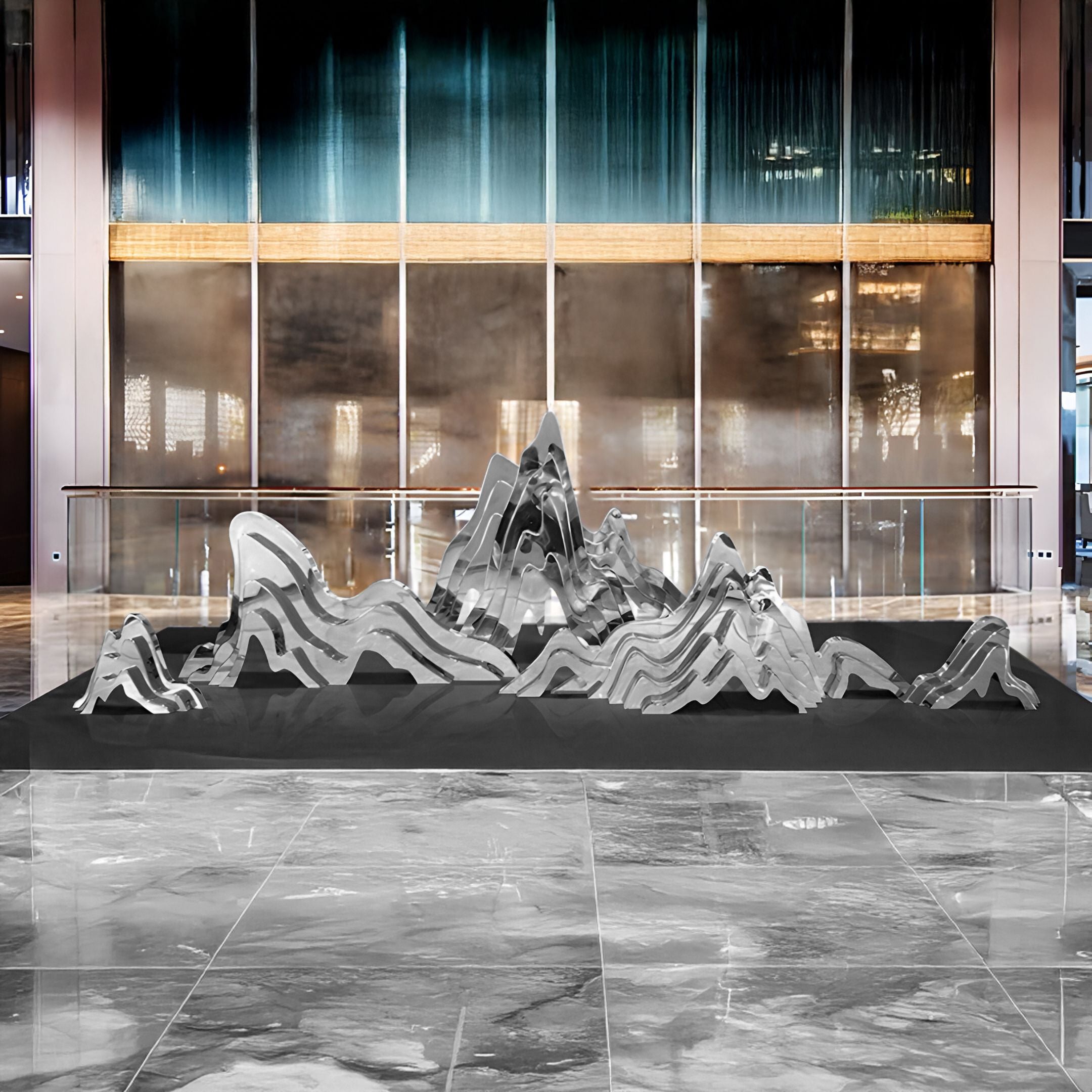 The Mountain Range Silver Abstract Steel Sculptures by Giant Sculptures stand indoors with reflective metallic forms, resembling mountain peaks. They are set against large glass walls with teal curtains and polished marble floors.