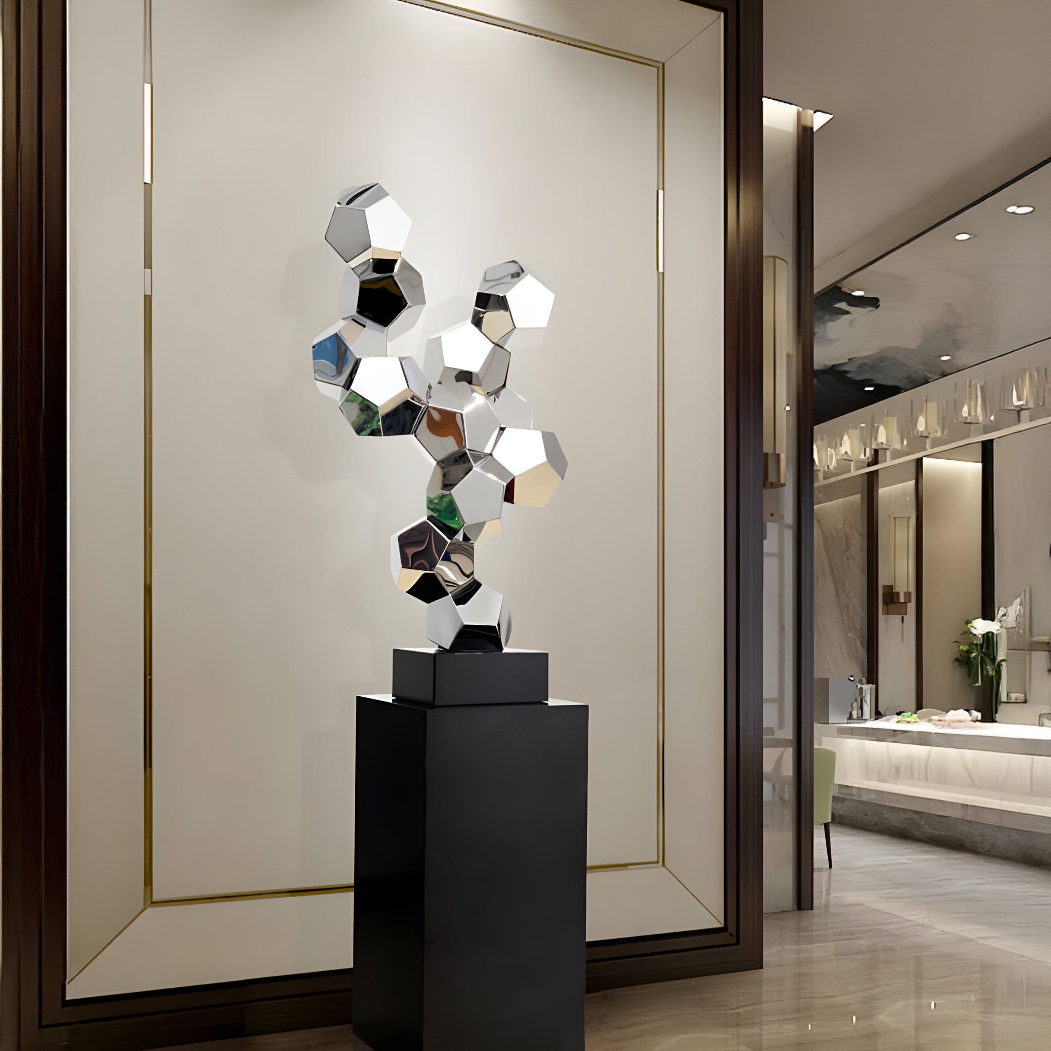 A silver geometric sculpture displayed in a luxury interior, placed against a marble wall.