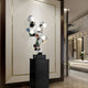 A silver geometric sculpture displayed in a luxury interior, placed against a marble wall.