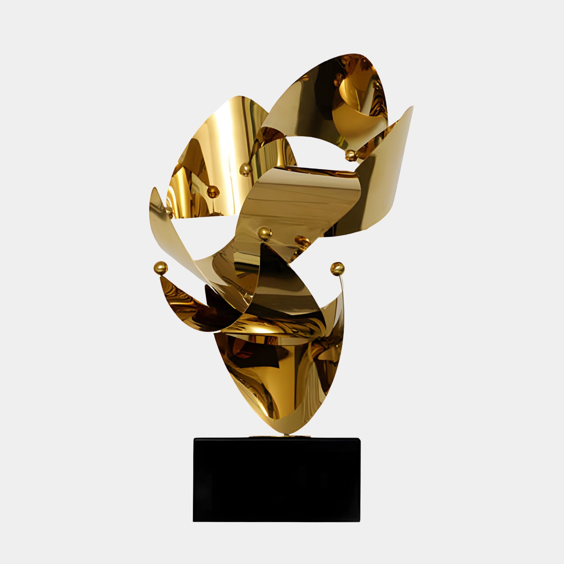 A gold abstract sculpture featuring smooth, flowing metallic shapes connected in a dynamic, modern design, placed on a black base.