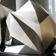 Close-up of the geometric facets of the silver dog sculpture, highlighting the angular lines and reflective surfaces.