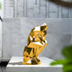 Full view of the gold human sculpture placed outdoors against a minimalist stone wall, enhancing the reflective properties of the golden material under natural light.