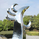 Polished silver phoenix sculpture in modern outdoor space.