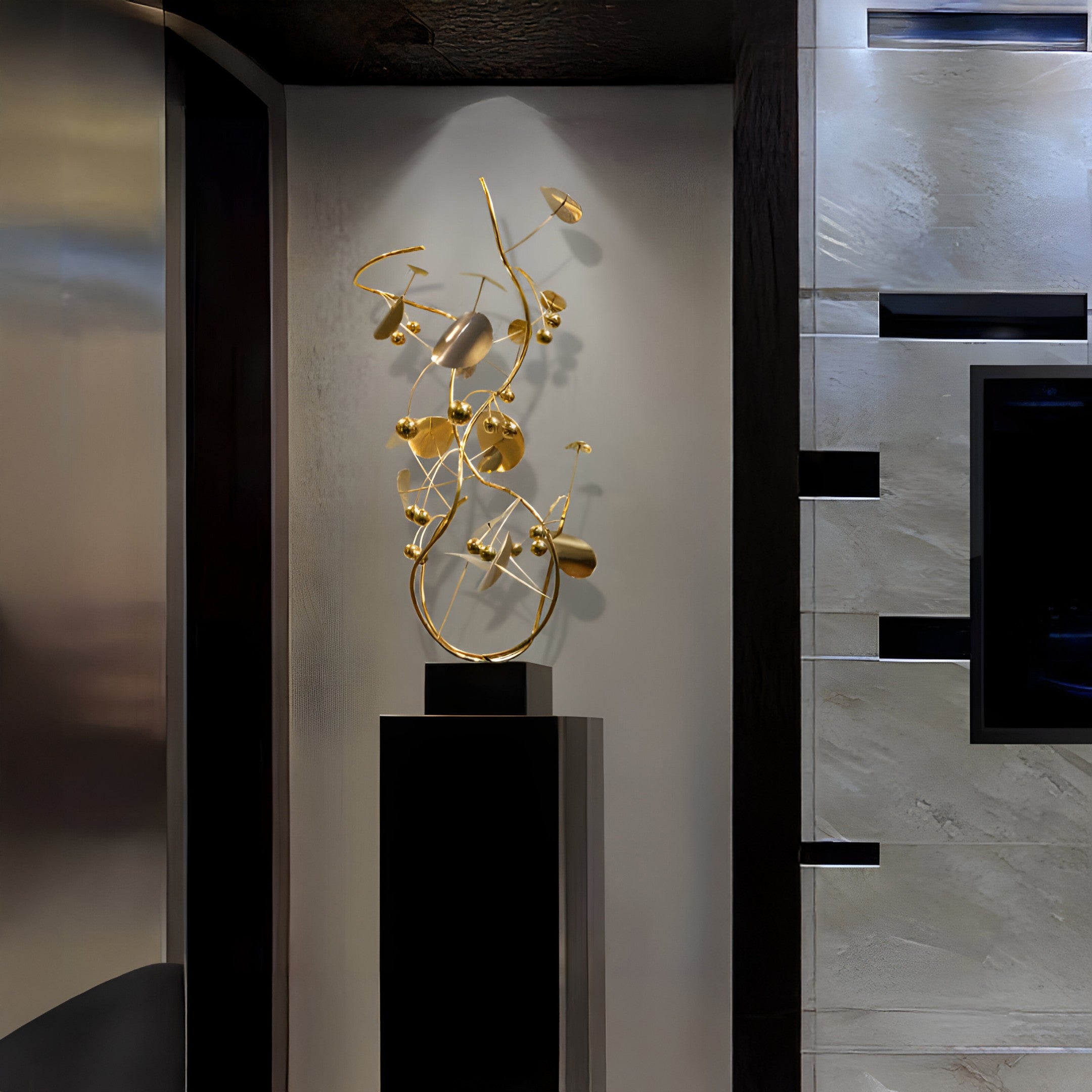 Gold sculpture displayed on a black stand against a contemporary interior setting.