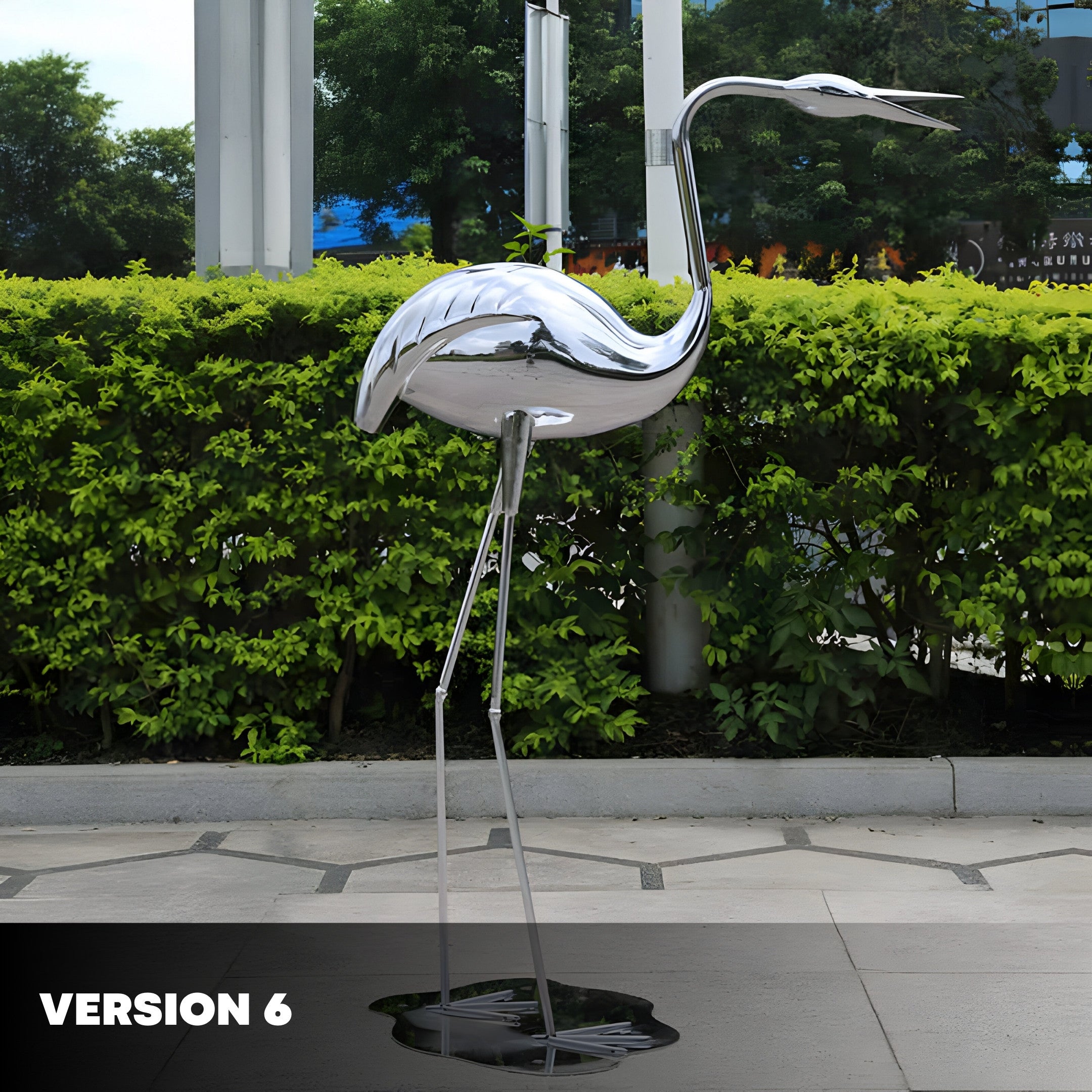 Another silver flamingo sculpture in the same outdoor setting with green hedges in the background, showcasing its curved, polished body and neck.