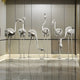 The flamingo sculptures displayed inside a modern showroom, creating a whimsical installation in an otherwise minimalist space.