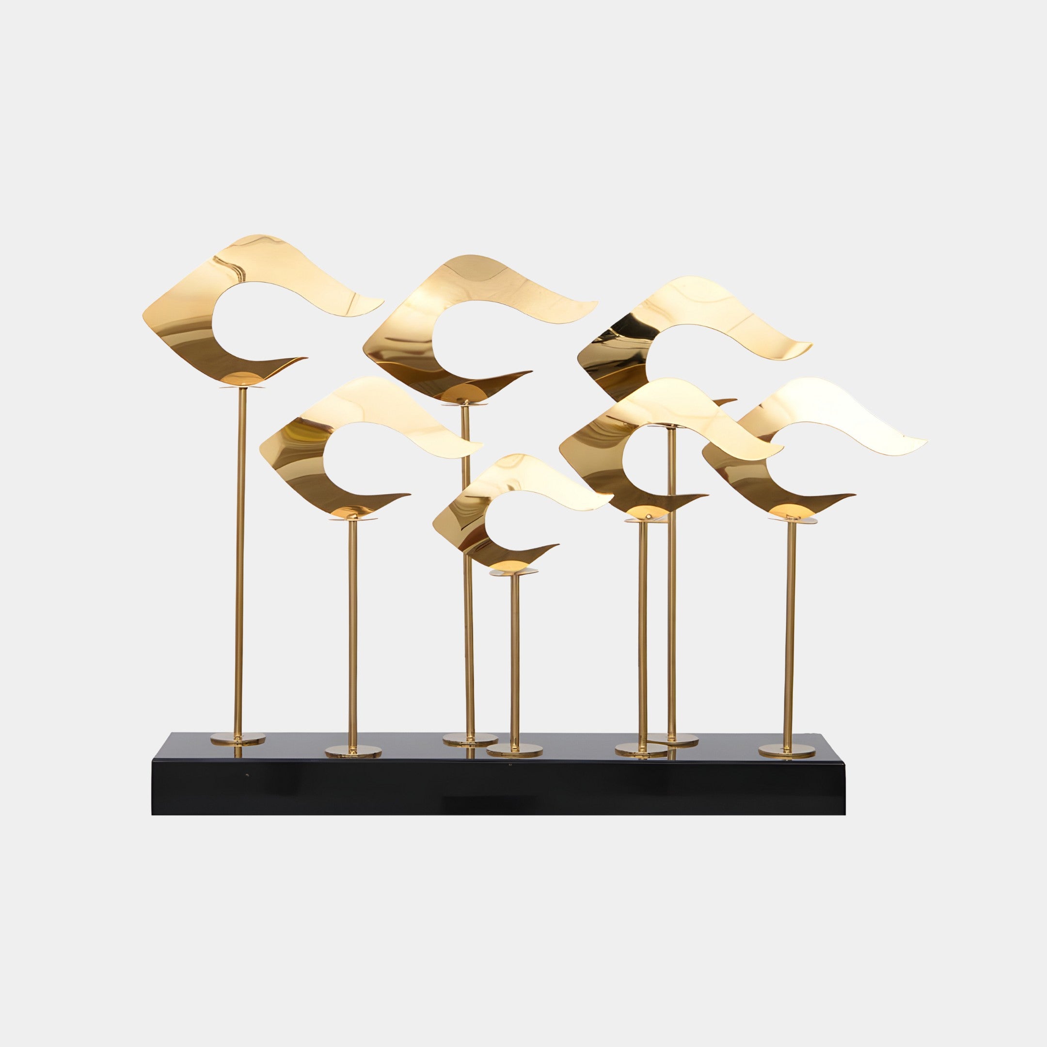 Group of abstract gold wave sculptures, standing tall on black metal poles, displayed on a black rectangular base.