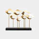 Group of abstract gold wave sculptures, standing tall on black metal poles, displayed on a black rectangular base.