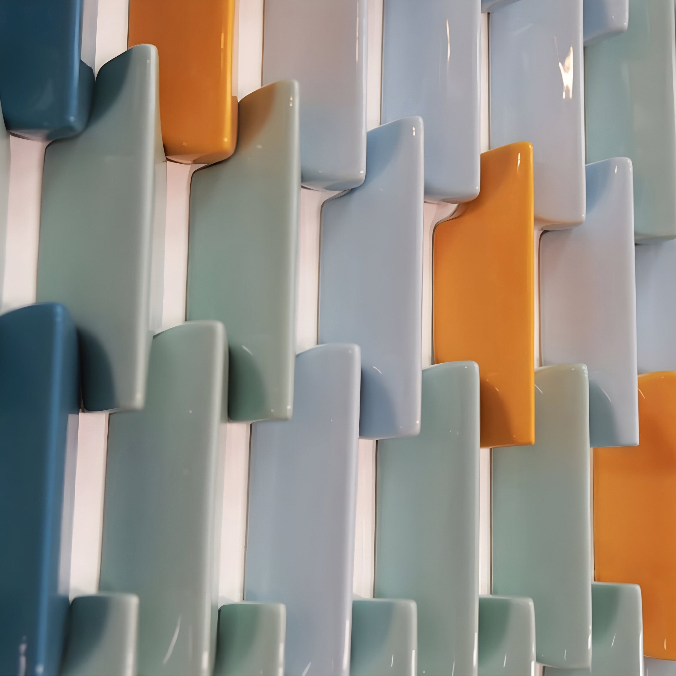 Close-up view of ceramic tile wall art showcasing glossy, rectangular pieces in blue, green, and orange hues. Each tile reflects light, highlighting its texture and smooth surface.