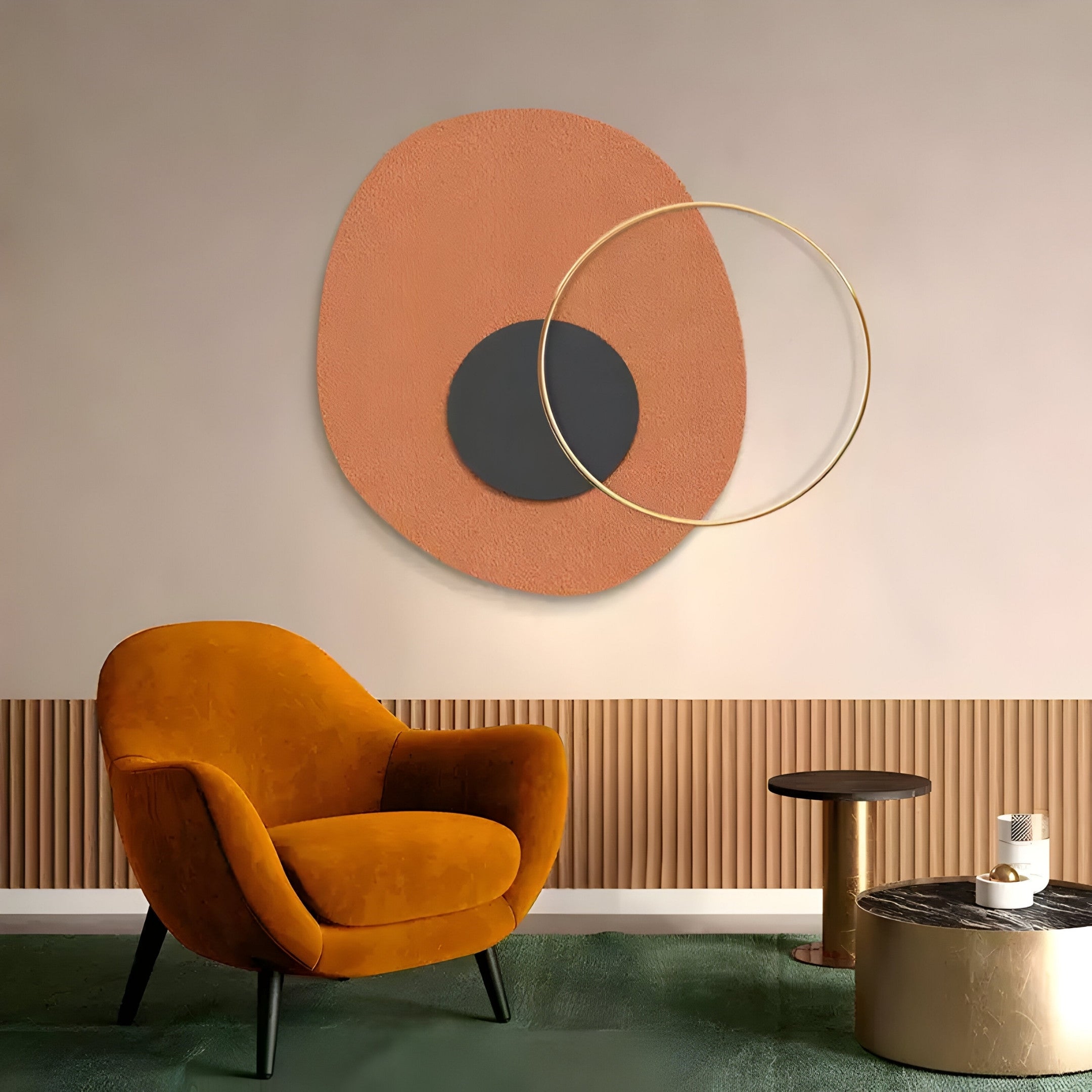 A modern living room includes a mustard yellow armchair, a gold side table, and the Giant Sculptures Solaro Earthy Terracotta & Black Round Mural Wall Art with abstract orange, black, and gold shapes. The green carpet and textured half-wall panel add rustic warmth.