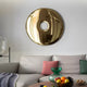 In a modern living room, a gold circular wall mirror and beige sofa with vibrant cushions create an aura of luxury. A glass coffee table with a fruit bowl beautifully complements the Auro Gold Round Gloss Metal 3D Wall Art by Giant Sculptures, merging contemporary and cozy vibes seamlessly.