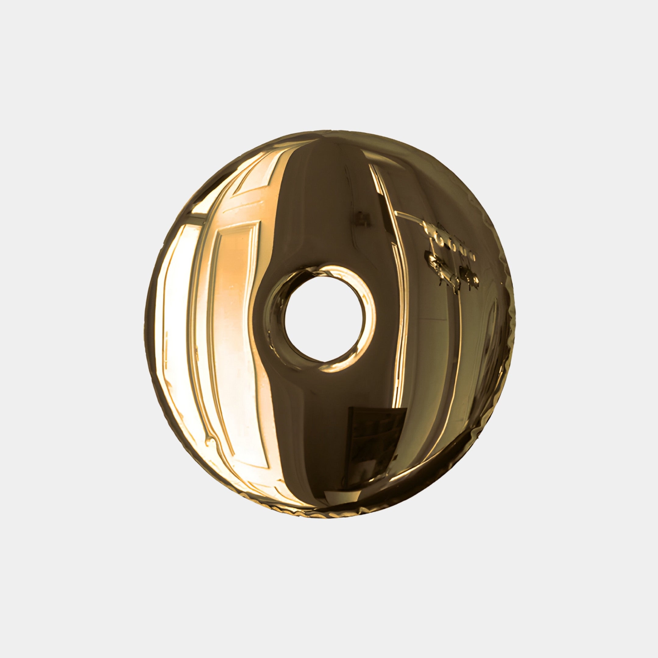 A glossy, metallic disc with a central hole, resembling the Auro Gold Round Gloss Metal 3D Wall Art by Giant Sculptures, against a light gray background. Its reflective surface distorts images and light, capturing modern design while adding abstract elegance to luxury interiors.