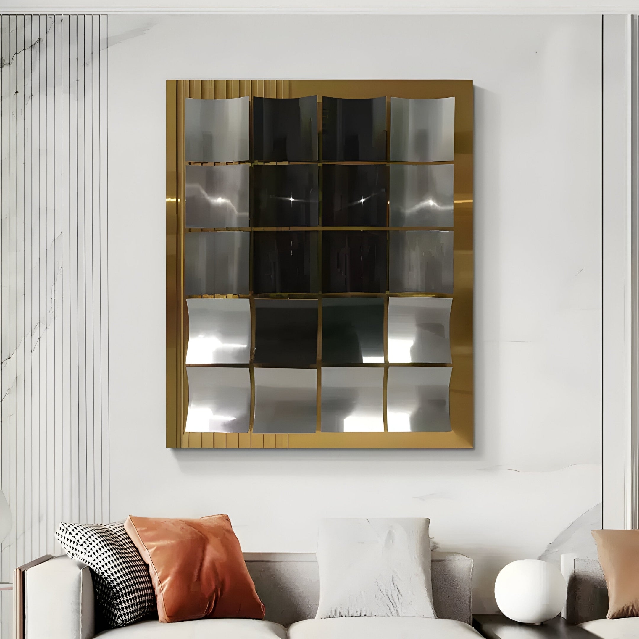 A modern living room features the Onda Gold & Silver Rippled Geometric Metal 3D Wall Art by Giant Sculptures, highlighting modern interiors. Cushions in orange, white, and gray adorn the sofa, while a round white lamp adds elegance on the side table.