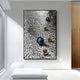 The Luminosa Blue & Gold Orb Textured Metal Wall Art by Giant Sculptures, a large abstract piece, is showcased in a modern, minimalist room with white walls and a bright window.