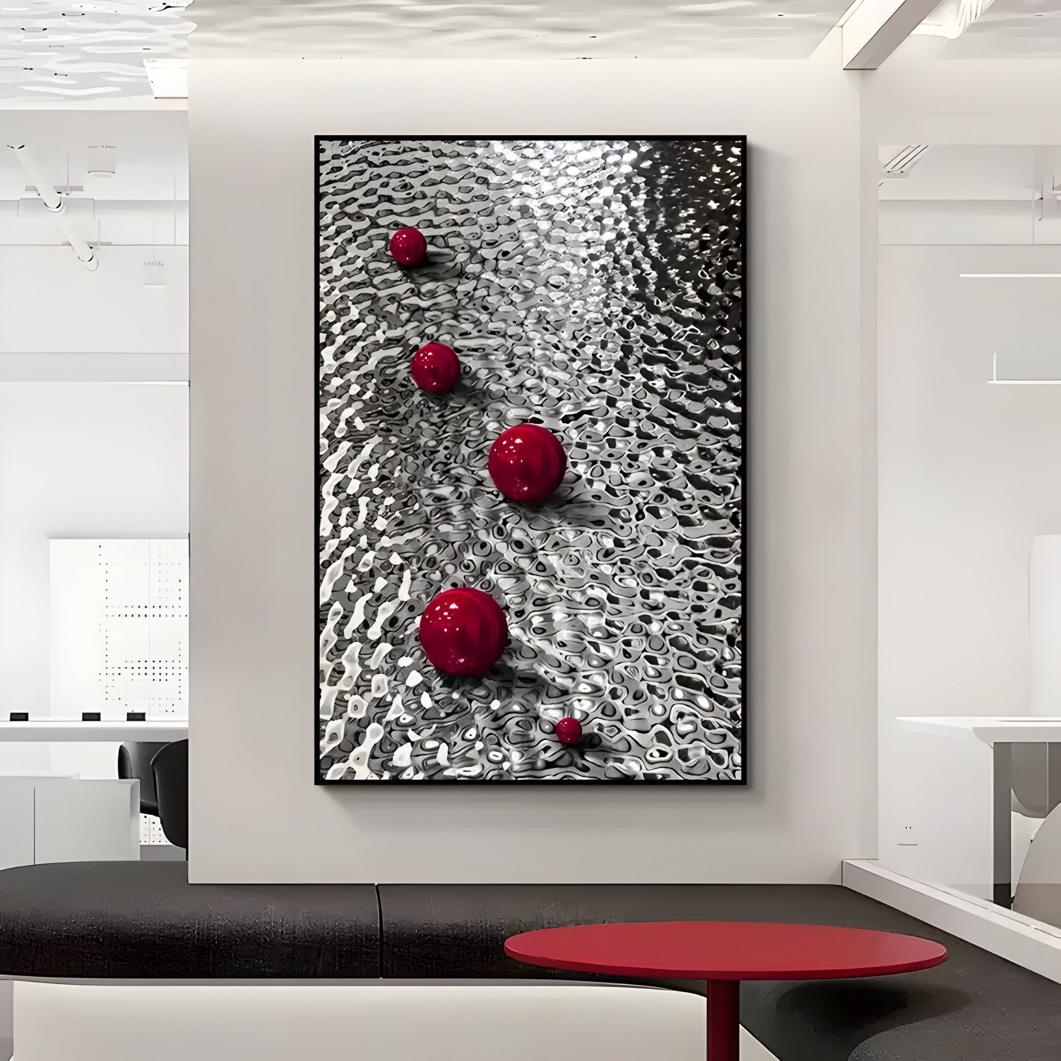 A black and white abstract artwork features Luminosa Red Orb Textured Metal Wall Art by Giant Sculptures, with five glossy spheres diagonally on a wavy surface. It is displayed in a modern, minimalistic room accented with textured metal art and black and red furniture.