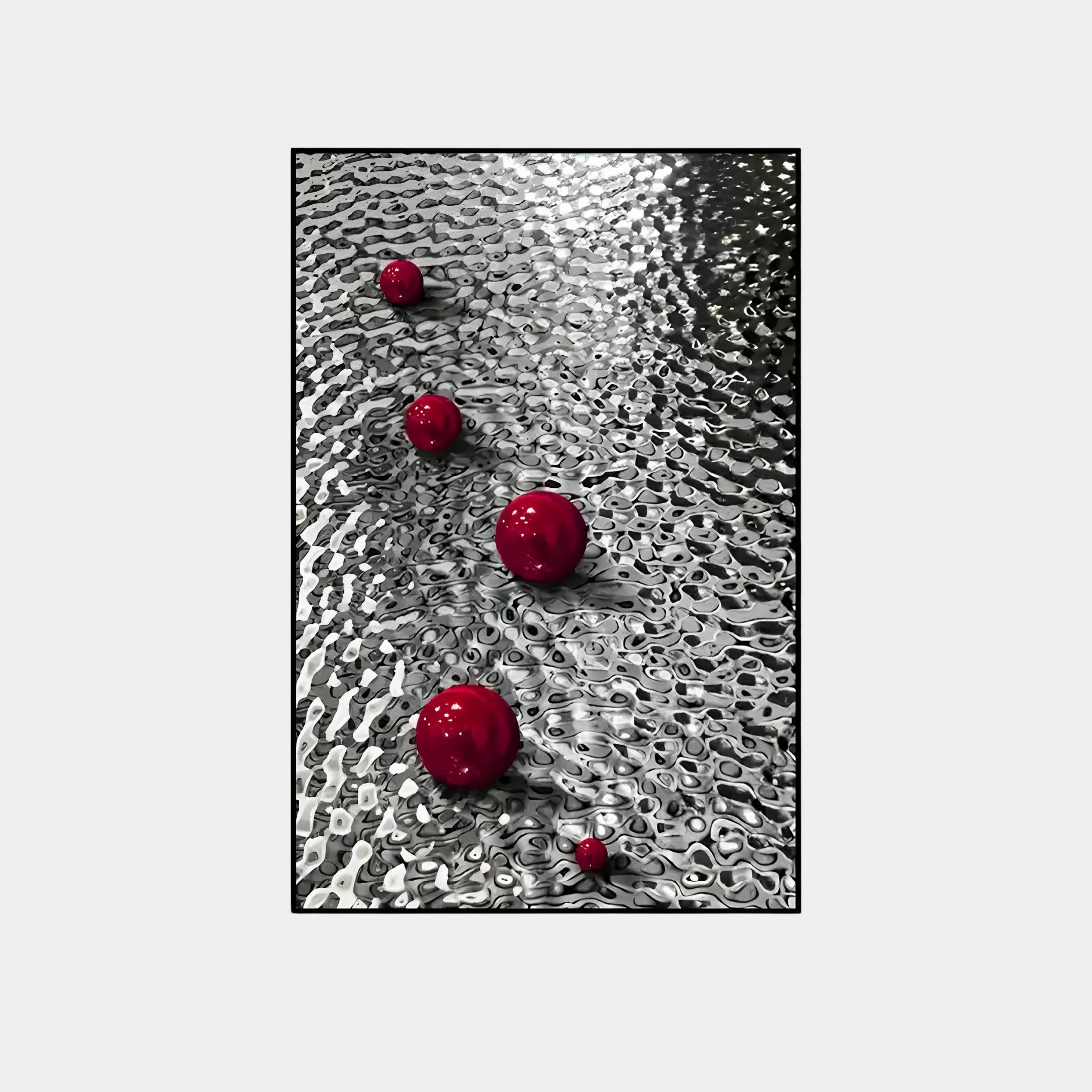 Giant Sculptures Luminosa Red Orb Textured Metal Wall Art features red orbs in various sizes on a rippled metallic surface. Expert lighting highlights the contrast between the shiny silver and bold red, crafting a striking modern decor piece with reflections and shadows.