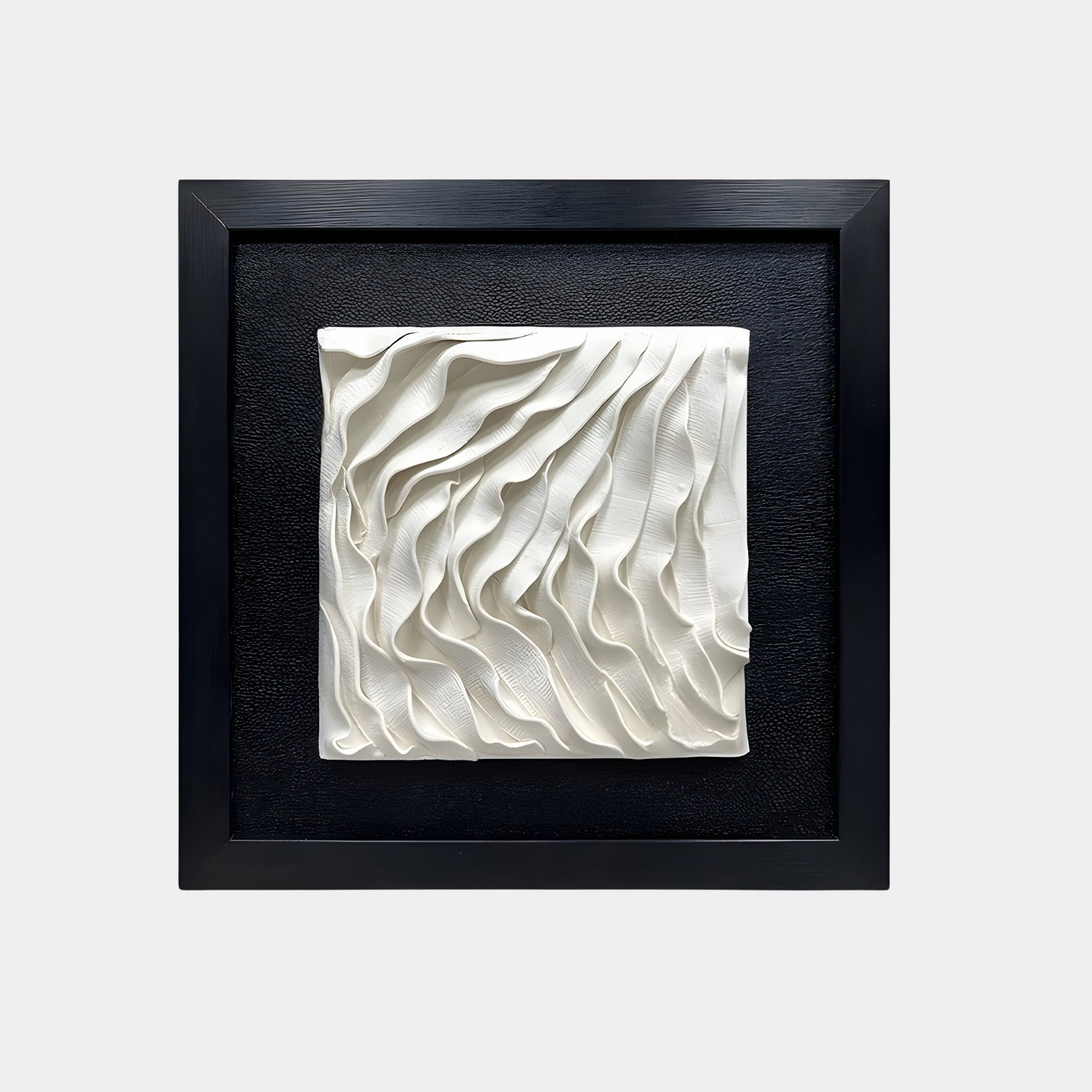 A framed ceramic wall art piece showcasing an abstract design of flowing, wave-like white patterns. The textured ceramic sculpture has layered, undulating curves that resemble ripples or draped fabric, adding depth and movement.