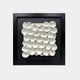 A framed white 3D wall art piece featuring sculpted circular shapes resembling delicate flower petals arranged in a grid pattern against a black background.