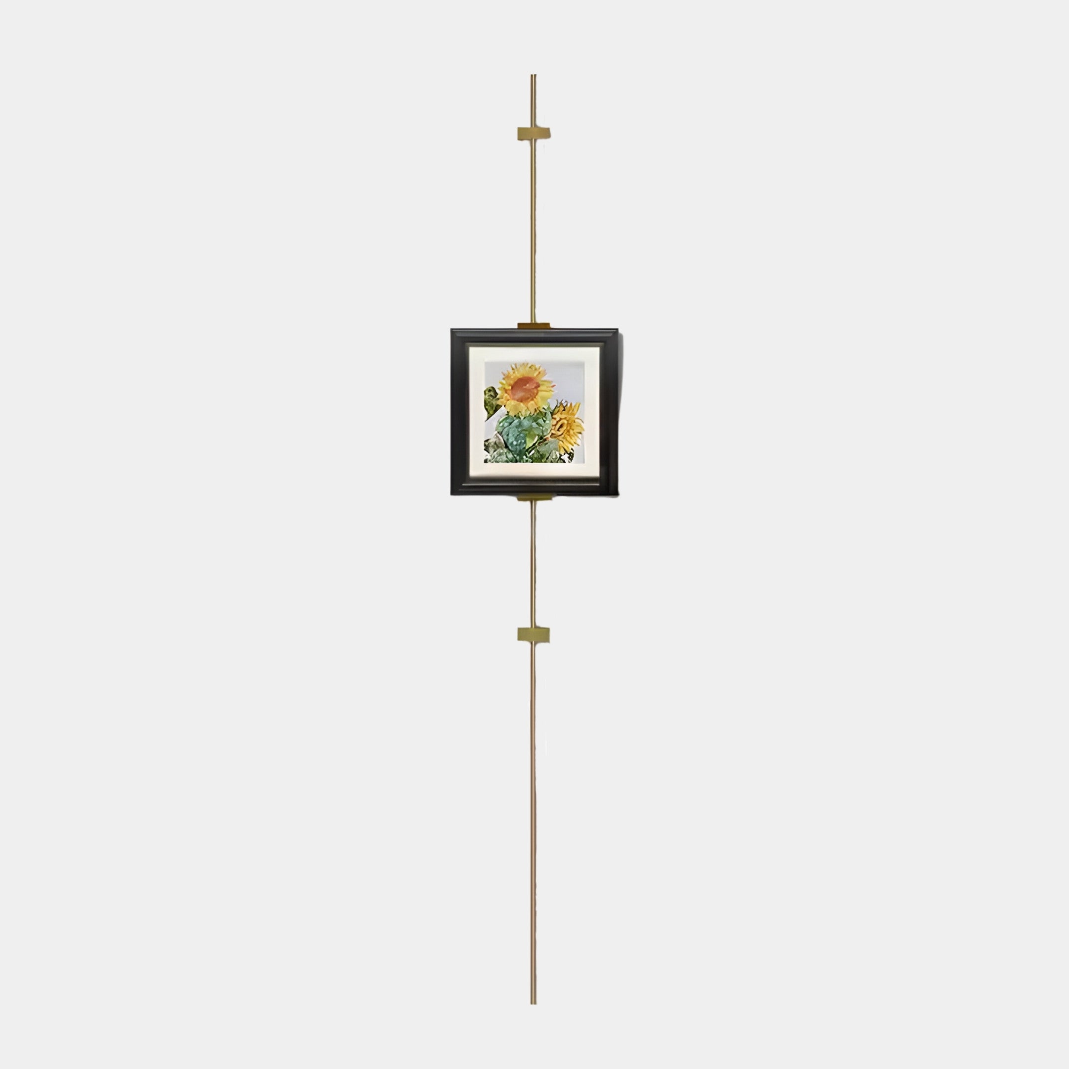 The Ecliptica Sunflower Botanical Illustration Gold Frame Wall Art by Giant Sculptures elegantly hangs on a vertical golden rod, showcasing modern design against a plain white background.