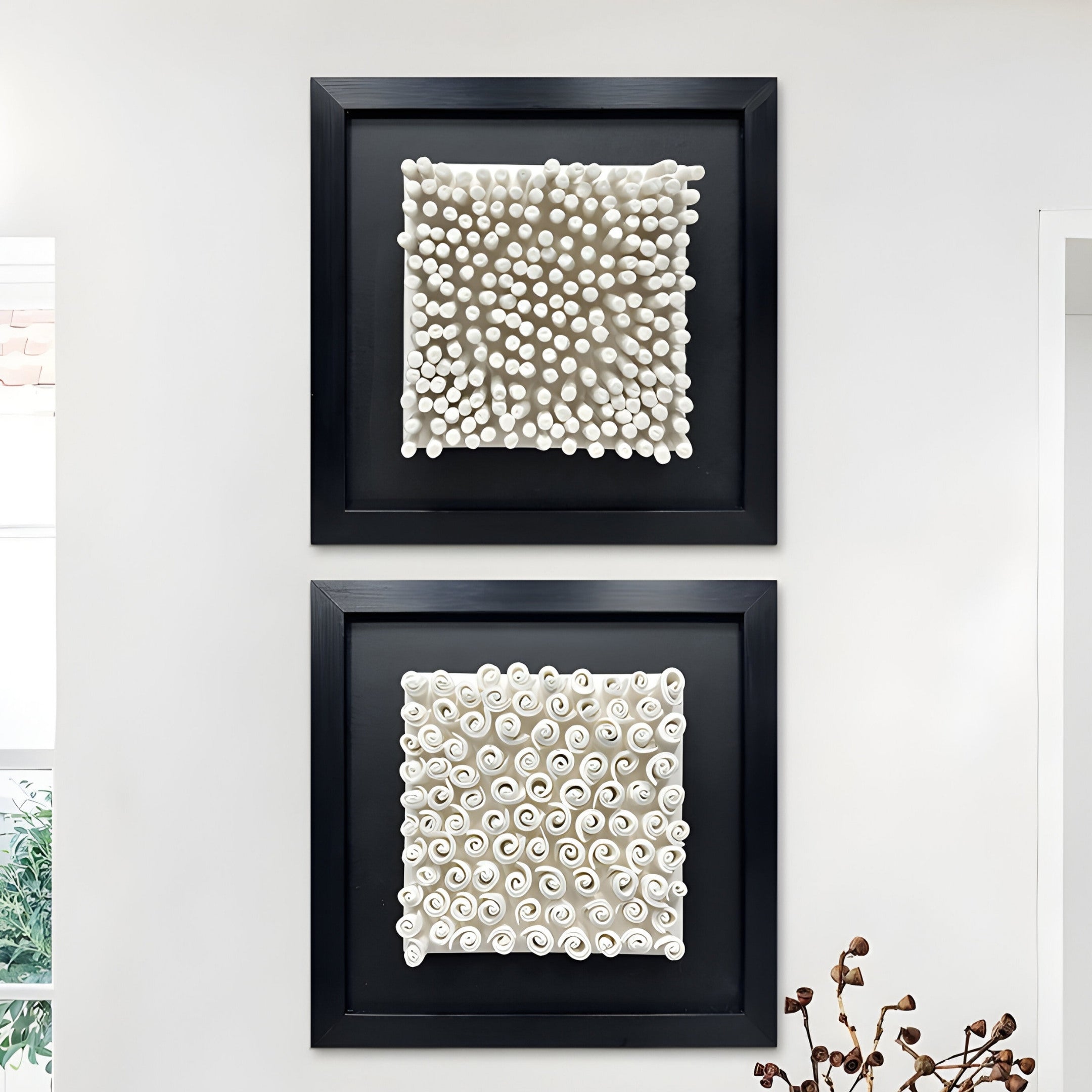 A square framed artwork featuring white ceramic spirals arranged in a grid pattern. Each spiral mimics delicate rolled paper or curled fabric, set against a black textured background.