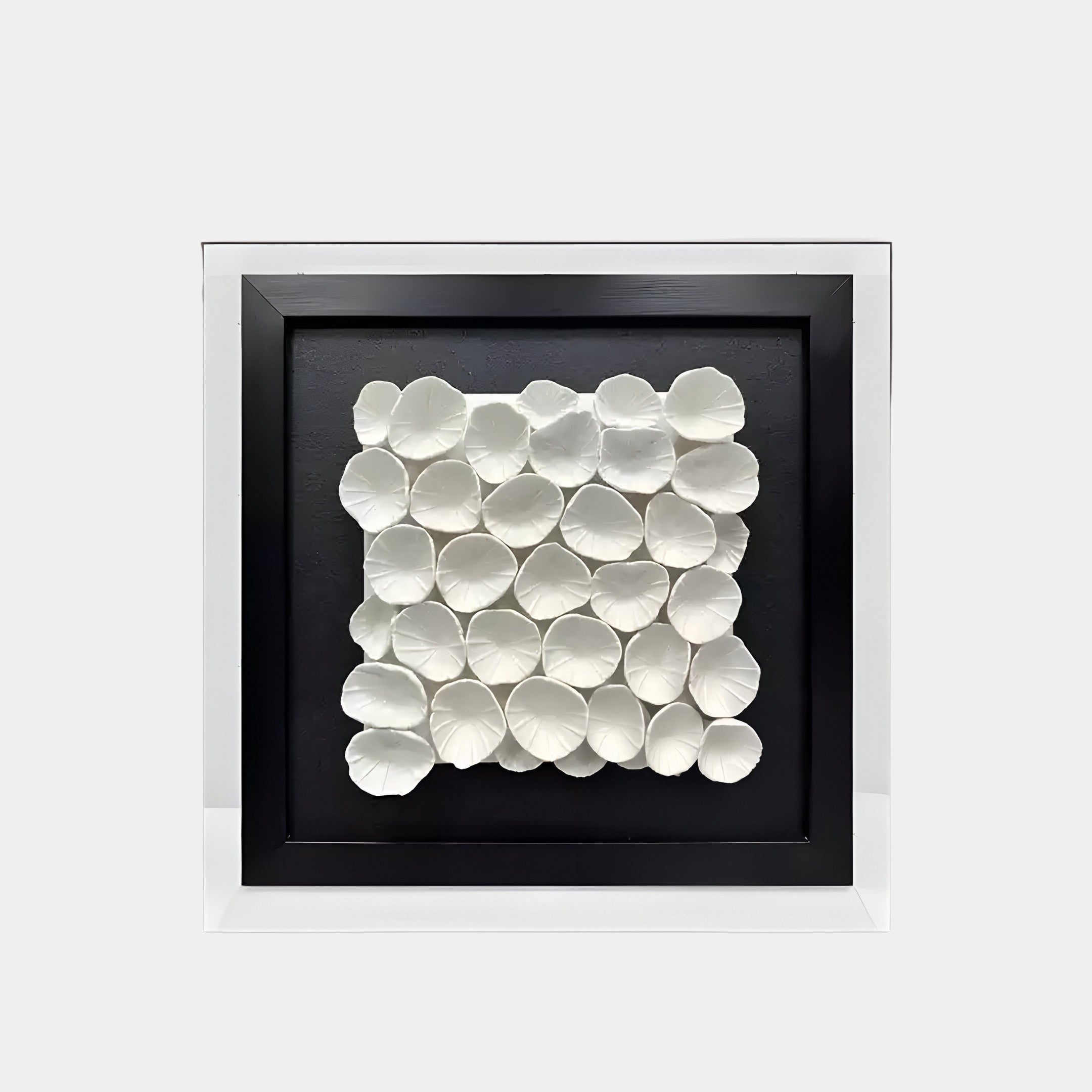 Modern 3D wall sculpture featuring white ceramic petal-like shapes arranged in a grid pattern on a black background. The textured design creates a soft, organic visual for contemporary interiors.