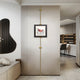 A sleek modern interior showcases the Ecliptica Red Mountain Abstract Wall Art by Giant Sculptures, framed in gold. To the left is a horizontal bench with cushions, while a kitchen area with bar and stools is visible in the background. The stone gray floor enhances this contemporary elegance.