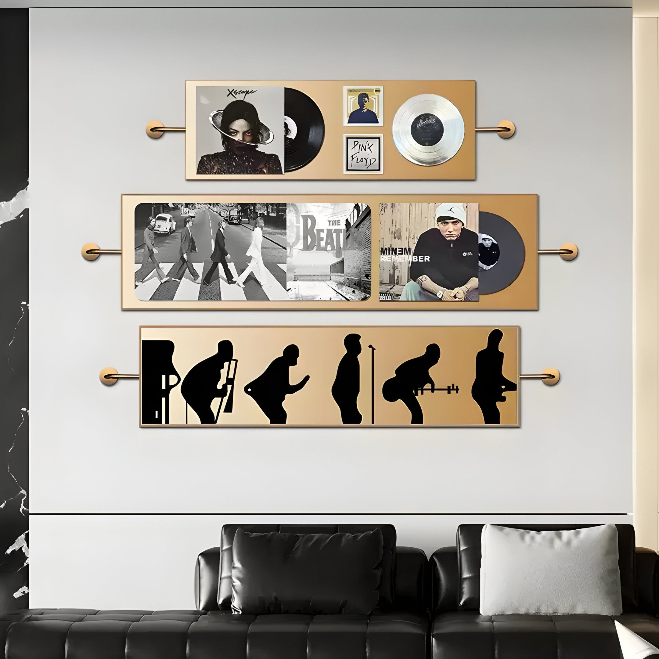 A stylish living room with a gray sofa and white pillow boasts three wall-mounted displays featuring Giant Sculptures Resonance Multi-Panel Record & Silhouette Wall Art, highlighting black musician silhouettes against a gold background.