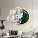 A modern living room features a white couch with gold and gray cushions, complemented by the Giant Sculptures Aurum Flora White Petals Jade Metal Wall Art. This decor showcases floral motifs on a circular green and black backdrop. A small statue enhances the elegant ambiance.