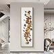 A modern interior features the Brassica Gold Leaf Metal Rectangular Wall Art by Giant Sculptures, showcasing gold and bronze designs on a light background. This piece is a focal point in a sleek room with marble floors, a sculpture, and contemporary lighting.