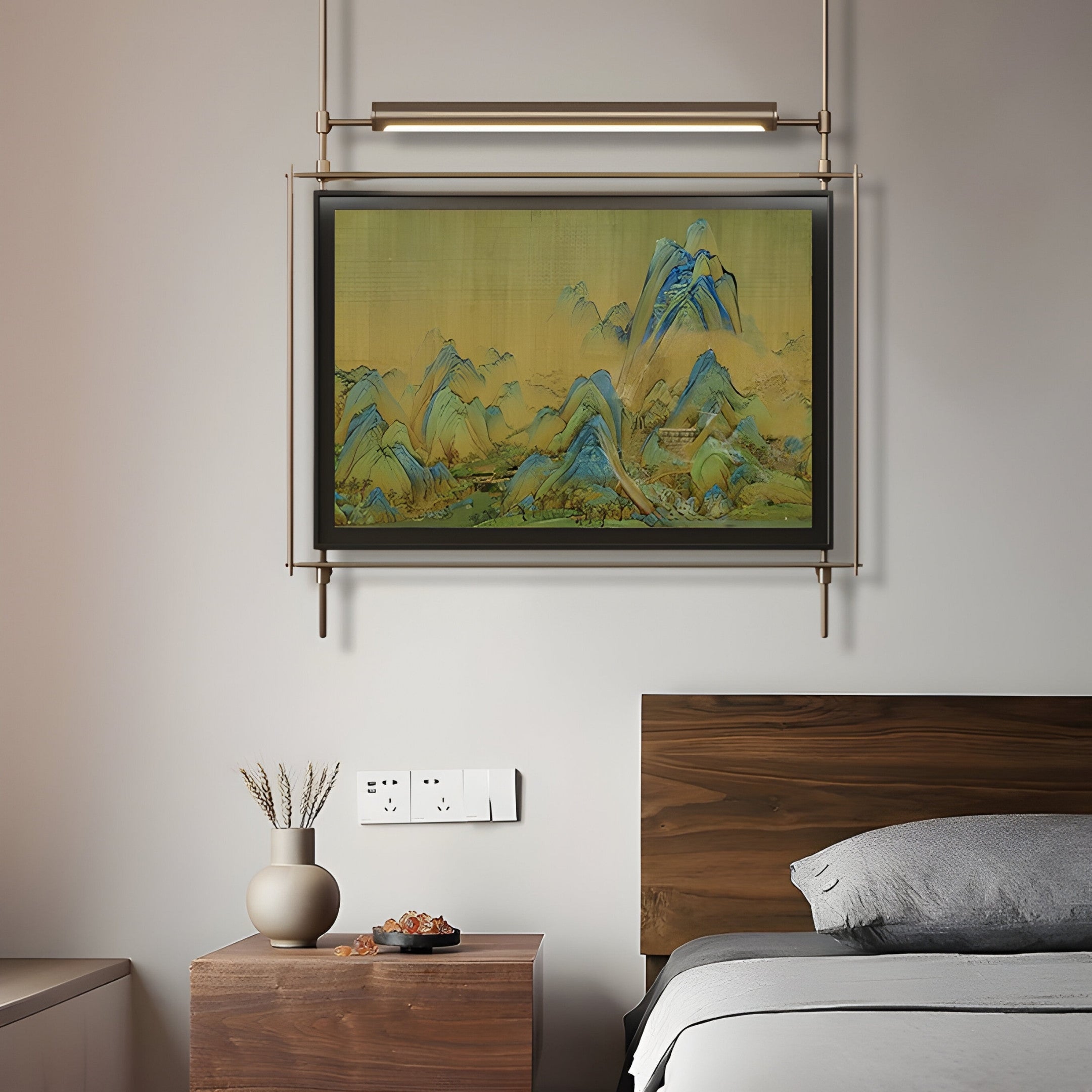 In a minimalist bedroom, a wooden bed with gray bedding is lit by Giant Sculptures Celestique Misty Horizons Framed LED Wall Art, showing blue-toned mountains against a yellow sky. A small vase with plant stems and a bowl on the side table enhance the rooms scenic beauty.