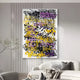 A modern living room features the Scriptura II Multicolour Graffiti Expression metal wall art by Giant Sculptures, boasting bold black, purple, and gold layers. It hangs above a white curved sofa with monochrome pillows while a minimalist dried branch adds a contemporary touch.