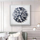 A modern room features Giant Sculptures Elysian 3D Ceramic Wall Art, showcasing navy blue, leaf-like shapes in a circular pattern. With white and gray pillows on the bed and two spherical pendant lights hanging from above, this sculptural artwork completes the chic modern ambiance.