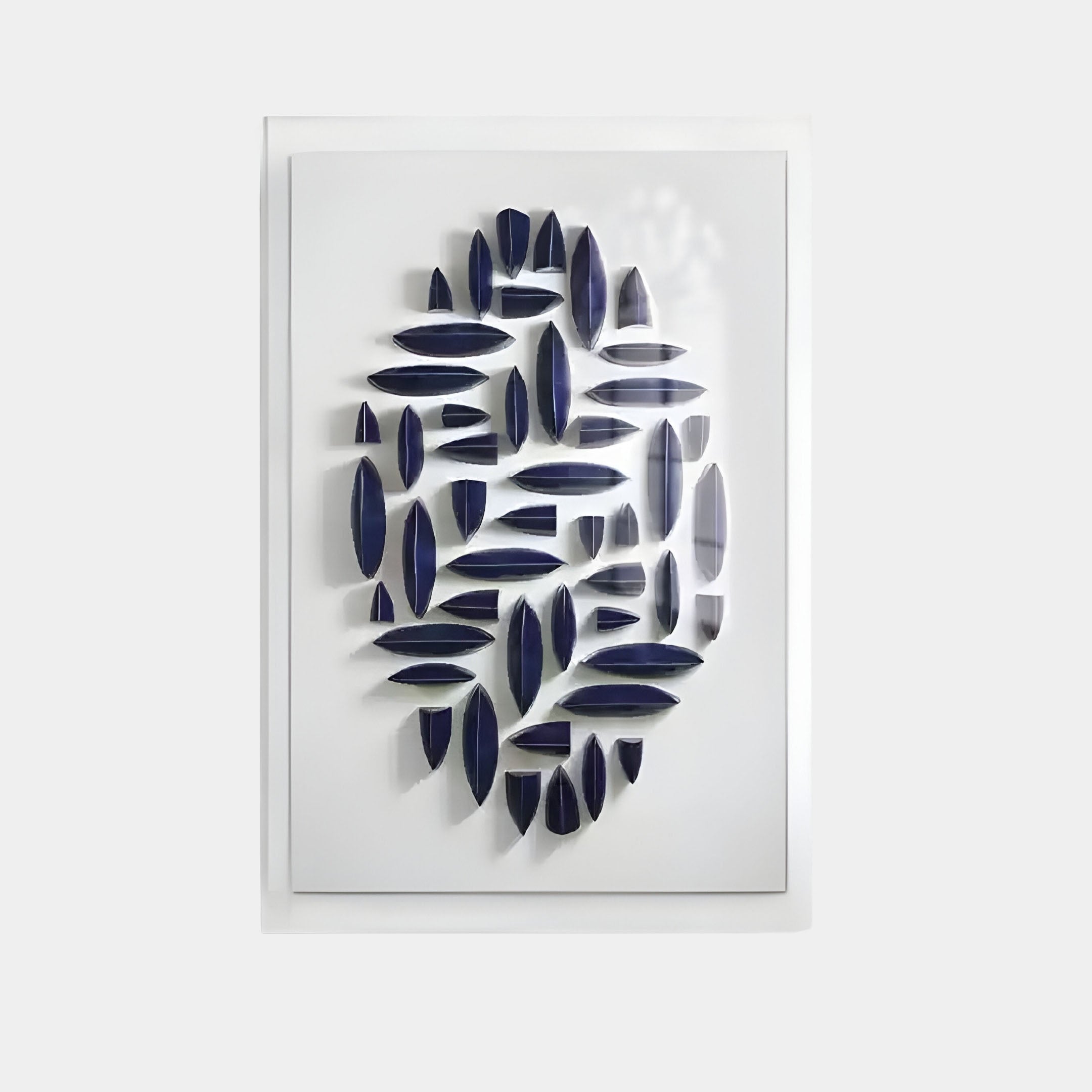 The Elysian 3D Ceramic Wall Art by Giant Sculptures features white rectangular frames with navy blue, boat-like shapes in a circular arrangement that cast subtle shadows, making it perfect for modern spaces.