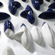 Close-up of glossy navy blue and white ceramic pieces from a modern 3D wall sculpture. The polished surfaces reflect light, showcasing the intricate craftsmanship.