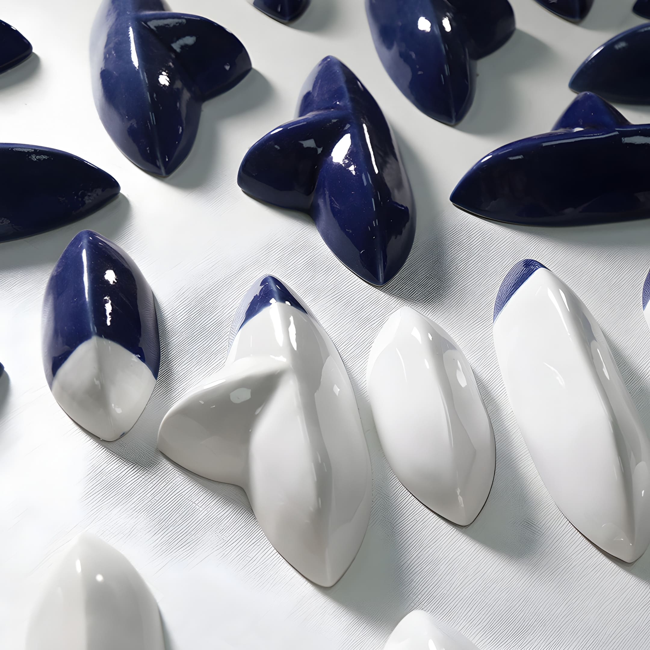 Close-up of glossy navy blue and white ceramic shapes from a 3D wall sculpture. The polished surfaces highlight texture and craftsmanship in the modern design.