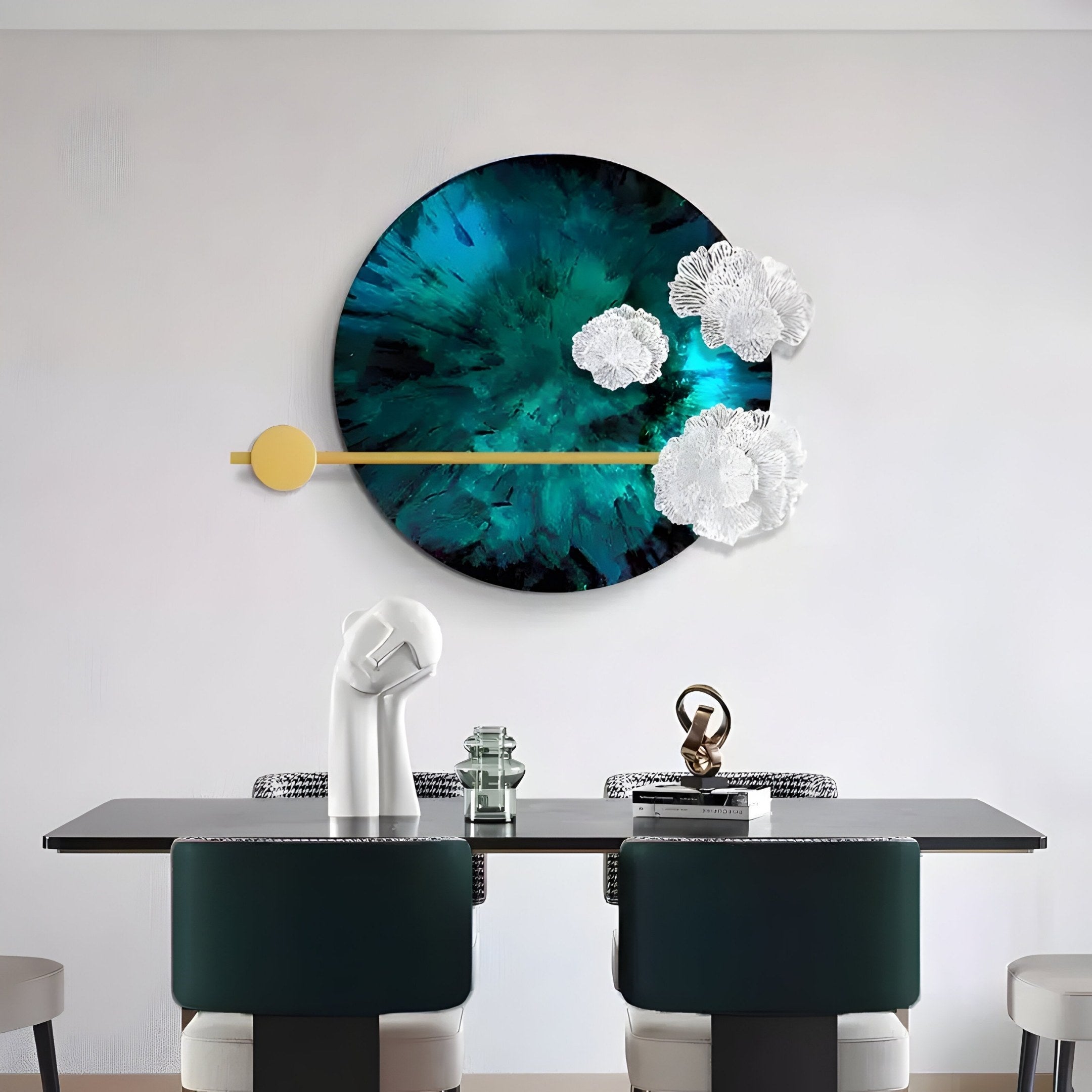 A sleek black table and two dark green chairs adorn the modern dining room, where the Giant Sculptures Nova Floral Radiant Teal Blue Circular Wall Art, with white floral accents and a golden rod, provides a striking backdrop embodying contemporary style.