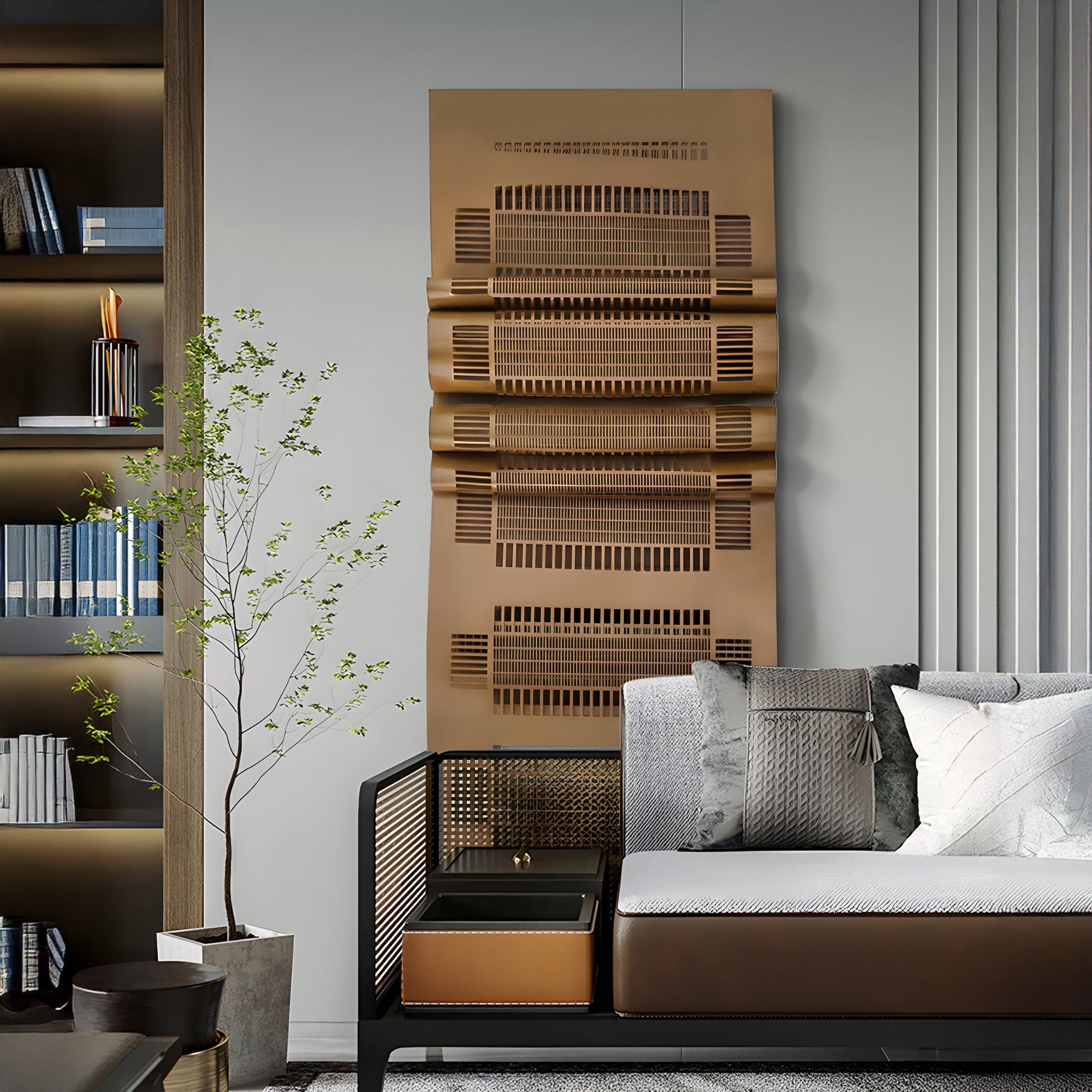 A modern living room features a sleek gray sofa with patterned cushions. Above it hangs the Strata Gold Vertical Folded Grid Metal Wall Art by Giant Sculptures. A small potted plant and a book-filled bookshelf complete this contemporary design.