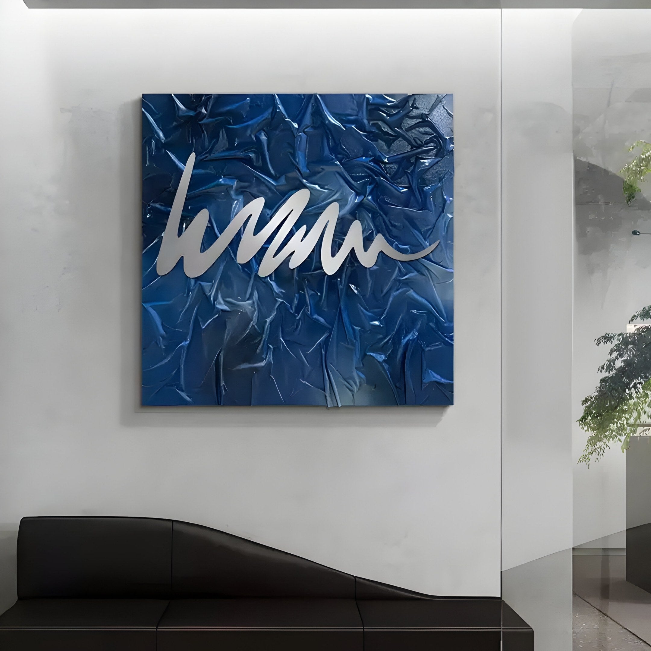 The Plisse Midnight Blue Textured Abstract Wall Art by Giant Sculptures, with silver scribble strokes, epitomizes modern decor on a white wall. Below it is a sleek black curved bench, and to the right, a glass partition reveals green plants.