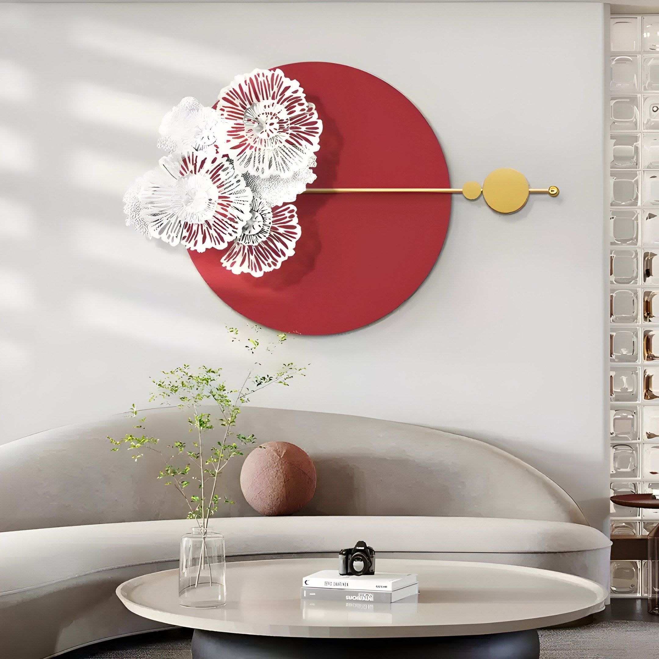 A modern living room features Giant Sculptures Blossom Halo Red Round Floral Decorative Wall Art, showcasing a large red circle and intricate floral accents. A curved gray couch and round coffee table with a small plant and book below complete the minimalist aesthetic.