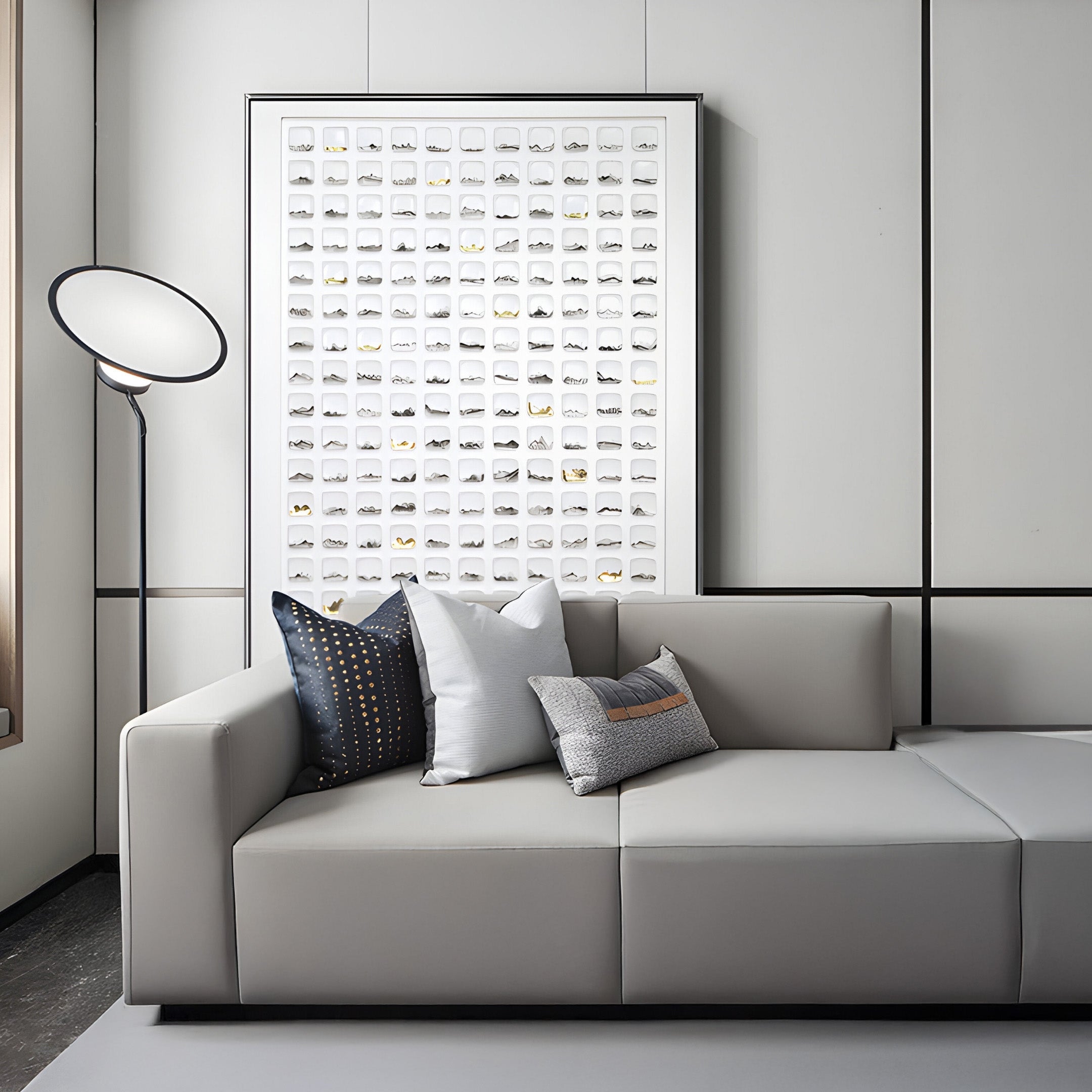 Large framed white ceramic tile art installation behind a gray sofa, featuring abstract black and gold accents for a luxurious and minimalist living room aesthetic.