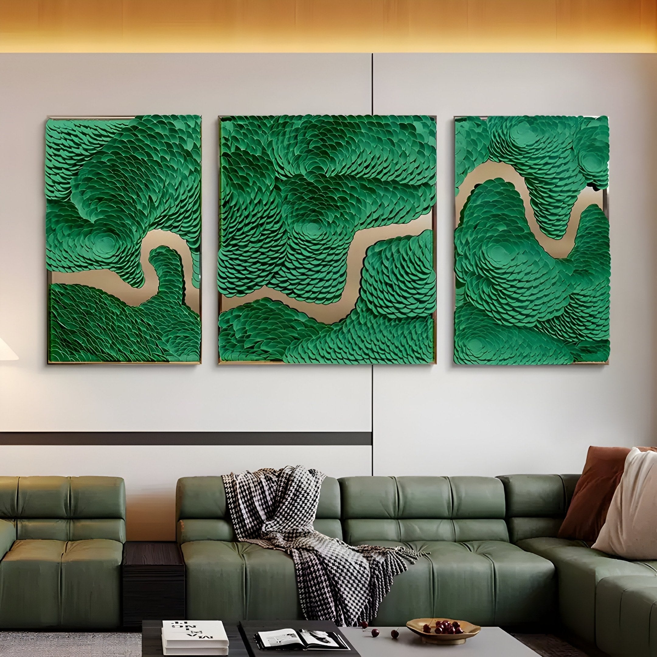 A contemporary living room features a green leather sofa with a blanket draped over its arm. The walls are adorned with the Riverine Flow Emerald Textured Triptych Wall Art by Giant Sculptures, showcasing swirling abstract patterns in green and beige. A lamp and decorative items complete this cozy space.