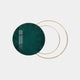 The Eclipse Luxe Velvet Emerald Circular Ring Wall Art by Giant Sculptures features a large dark green circle slightly overlapping two thin gold rings on a light gray background, with a window reflection adding depth to this contemporary decor piece.