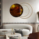 A modern living room includes a white curved sofa, illuminated by the Eclipse Luxe Amber Glow Circular Ring Wall Art by Giant Sculptures. A round marble coffee table and intersecting circle-themed decor elements complete the space, enhanced with decorative plants and soft lighting for coziness.