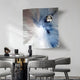 A modern dining area highlights a round table with four chairs and the Astralis Frostflare Radiant Abstract 3D Wall Art by Giant Sculptures, displaying a distorted radial blur of blue and white hues. Contemporary decorative items adorn the table, enhancing the elegant ambiance.