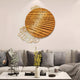 A modern living room showcases contemporary home decor with gray sofa cushions and Giant Sculptures Auramesh Sunset Orange-I Metal Winged Circular Geometric Wall Art. A coffee table features a vase of yellow flowers and a small plant, adding natural elegance to the sleek setup.