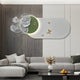 A modern living room features a sectional sofa, the Flutter Bloom Green Butterfly Floral 3D Wall Art by Giant Sculptures with large silver flowers, and golden butterflies. A black coffee table with dried flowers and a fruit tray complements the decor.