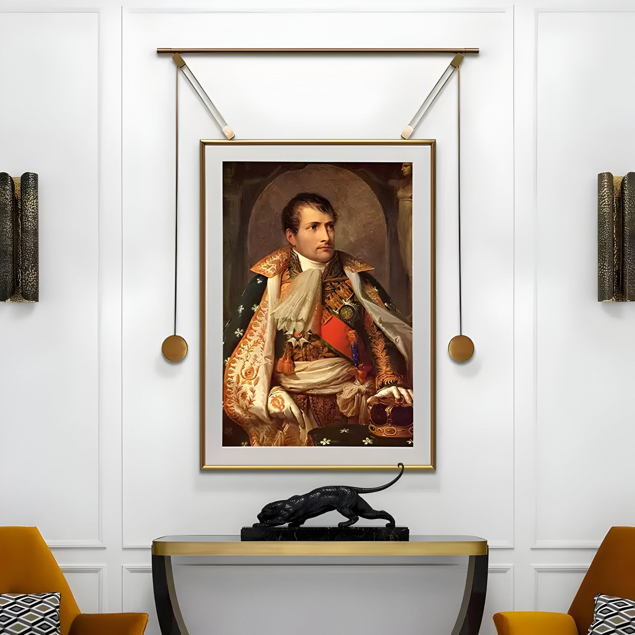 The Aristo Napoleon Portrait Painting Gold Frame Wall Art by Giant Sculptures hangs in a white-walled room. Below it, a black panther statue is displayed on a modern shelf, while patterned cushions and wall sconces accent the space.