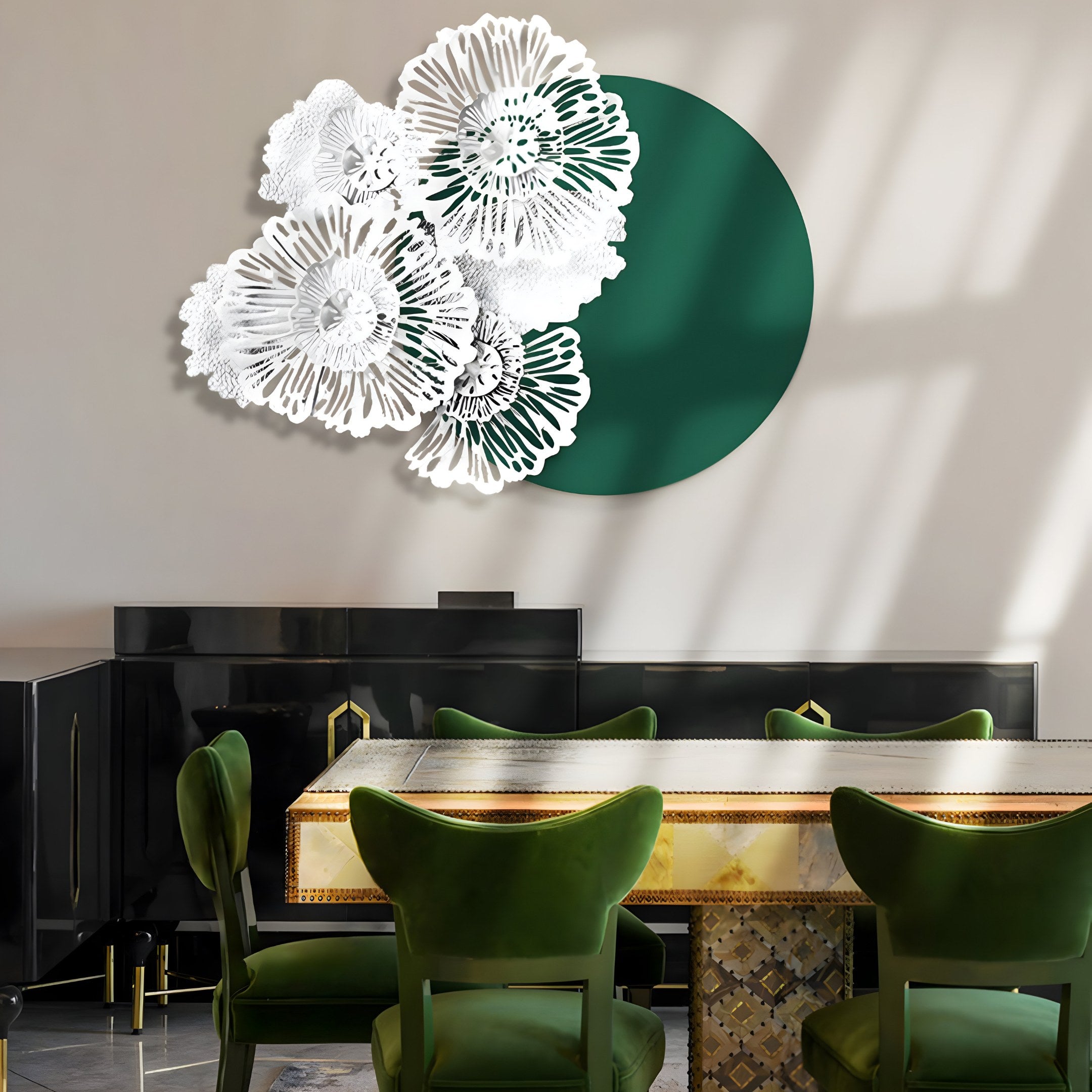 An elegant dining room showcases Giant Sculptures’ Fleur Halo Green Round White Metal Floral Decorative Wall Art. It features a polished golden table and plush green chairs, complemented by window shadows and high-quality iron elements for an industrial charm.