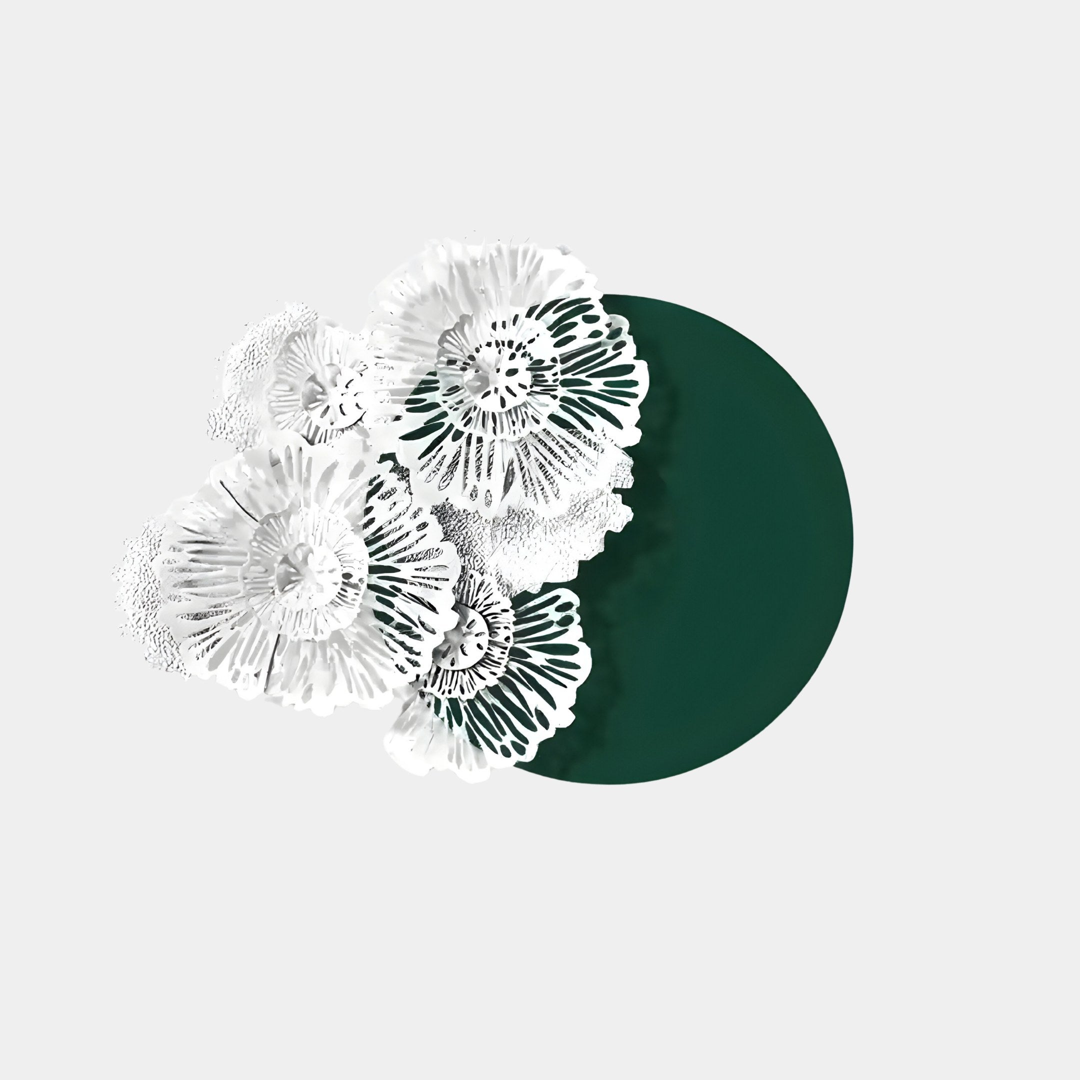 The Fleur Halo Green Round White Metal Wall Art by Giant Sculptures features intricate white lace-like flowers over a dark green circle on a light gray background, elegantly contrasting floral design with bold geometric elements for a stunning decorative piece.