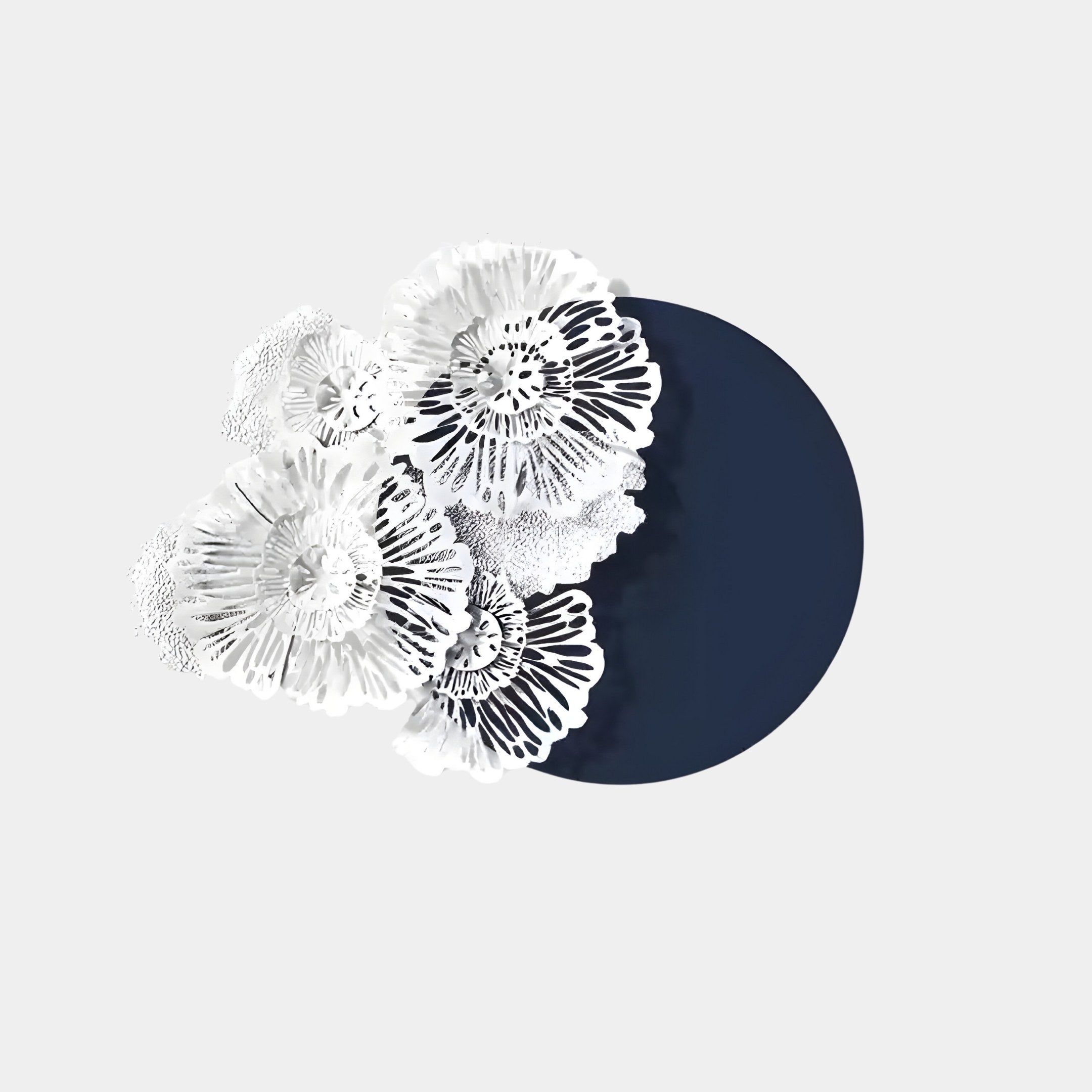 The Fleur Halo Navy Blue Round White Metal Floral Decorative Wall Art by Giant Sculptures features intricate white floral designs on a dark blue circular background, creating a striking piece against a light grey backdrop.